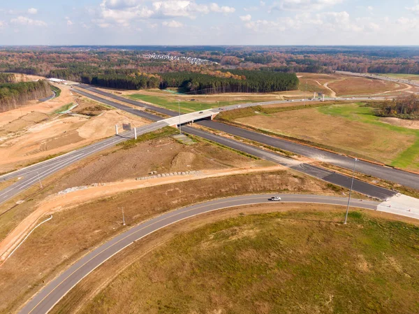 Bu hava çekimi Kuzey Carolina, Raleigh yakınlarındaki 40 numaralı otoban otobanındaki karmaşık türbin kavşağını gösteriyor. Karmaşık yol sistemi verimli Piedmont ormanları boyunca dokumakta, modern altyapıyı, yoğun trafiği ve bölgenin geniş çapını gözler önüne sermektedir..