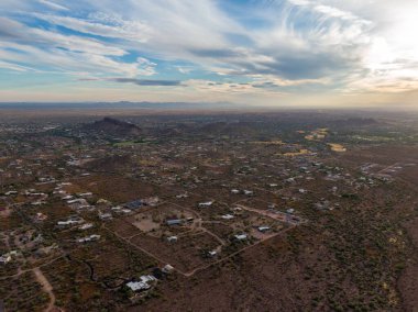 AZ, Gold Canyon 'daki lüks çöl arazisinin insansız hava aracı görüntüsü. Batıl inanç dağlarının eteklerinde yer alıyor. Parlak, parçalı bulutlu bir gökyüzünün altında geniş Sonoran Çölü manzarasıyla çevrili fayanslı çatıları olan büyük gümrük evleri..
