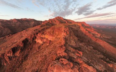 Altın Kanyon, AZ 'deki güneşten sırılsıklam olmuş Batıl inanç Dağları' nın insansız hava aracı görüntüsü. Altın saat ışığı engebeli volkanik kaya yüzeylerinde ve çöl sırtlarında parlar. Uçsuz bucaksız Sonoran Çölü 'nün üzerindeki devasa uçurum kulesi yumuşak, boyalı günbatımı gökyüzünün altında..