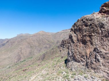Batıl inanç Dağları 'ndaki volkanik bir uçurumun havadan görünüşü. Öğleden sonra ışığı, Arizona Gold Canyon yakınlarındaki Sonoran Çöl Vadisi 'ne bakan engebeli dokuları ve çöl çalılarını yakalar. Gün batımında çarpıcı güneybatı vahşi doğası.