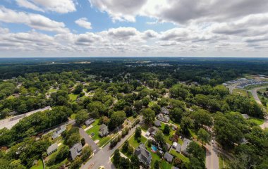 Wendell, Kuzey Carolina 'daki yemyeşil bir yerleşim bölgesinin yüksek irtifa hava aracı görüntüsü. Görüntü, yoğun yeşil ağaçların arasına yuva yapmış evleri gösteriyor. Uçsuz bucaksız bir gökyüzünün altında dağınık beyaz bulutlu..
