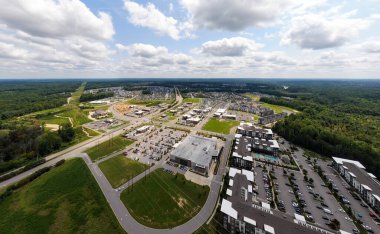 Wendell, Kuzey Carolina 'daki Treelight Meydanı' nın geniş bir insansız hava aracı görüntüsü. Sahne, yüzme havuzları, geniş perakende otoparkları ve parlak bir gökyüzü altında yeni ticari büyüyen modern çoklu aile apartmanlarını ön plana çıkarıyor..
