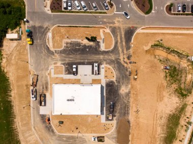 Wendell, Kuzey Carolina 'daki ticari bir inşaat alanının yukarıdan aşağıya insansız hava aracı görüntüsü. Görüntü, kentsel kalkınma ve altyapının ilk aşamalarını yakalayan bir yapı, ağır makineler, iş kamyonları ve derecelendirilmiş toprağı gösteriyor..