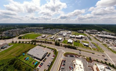 Wendell, Kuzey Carolina 'nın modern banliyö gelişimini gösteren yüksek açılı insansız hava aracı görüntüsü. Hava perspektifi ticari perakende binalar, otoparklar, yerleşim evleri ve parlak, bulutlu bir gökyüzü altında yemyeşil alanlar karışımını yakalıyor..
