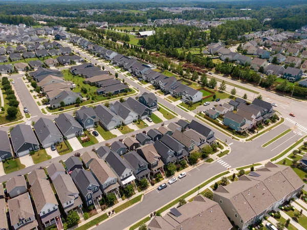 Wendell, Kuzey Carolina 'da yayılan modern yerleşim alanının insansız hava aracı görüntüsü. Görüntü, çağdaş çok katlı evler, temiz banliyö sokakları ve parlak, parçalı bulutlu bir yaz gökyüzü altında manikürlü manzaraları yakalıyor..