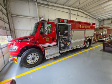 Beyaz Seviye İtfaiye Departmanı 92 'nin yan görüntüsü. İstasyon bölümüne park etmiş kırmızı bir pompa kamyonu. Araçta altın renkli 