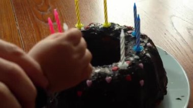 Tahta bir masanın üzerinde ev yapımı çikolatalı kekin üzerindeki anne yıldırım mumlarının yakın plan detayları. Evde doğal pencere ışığıyla aile kutlaması. Yüksek kalite 4k görüntü