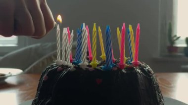 Tahta bir masanın üzerinde ev yapımı çikolatalı kekin üzerindeki anne yıldırım mumlarının yakın plan detayları. Evde doğal pencere ışığıyla aile kutlaması. Yüksek kalite 4k görüntü