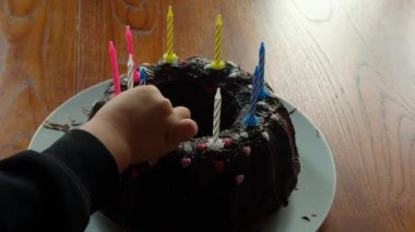 Evde doğal pencere ışığıyla aile kutlaması. Çikolatalı kekin üzerine mum koyan bir anne ve çocuğun yakın plan görüntüleri. Yüksek kalite 4k görüntü