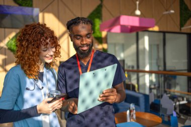 Doktorlar ve doktorlar hastane kafeteryasındaki dijital tabletlerin hasta tabletlerini hastane kafeteryasındaki dijital tabletlerin çizelgelerini tartışıyorlar. Yüksek kalite fotoğraf