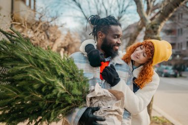 Yaklaşan tatiller için aldıkları Noel ağacını taşıyan mutlu bir çift. Yüksek kalite fotoğraf çeken mutlu bir çift Noel ağacı taşıyor ve gelecek tatiller için satın alıyorlar.