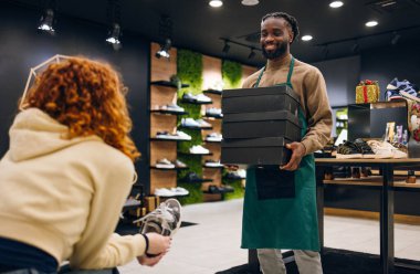 Ayakkabı mağazasında kutu taşıyan bir ayakkabı satıcısı. Ayakkabı mağazasında kutu taşıyan kaliteli bir ayakkabı satıcısı.