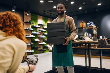 Ayakkabı mağazasında kutu taşıyan bir ayakkabı satıcısı. Ayakkabı mağazasında kutu taşıyan kaliteli bir ayakkabı satıcısı.