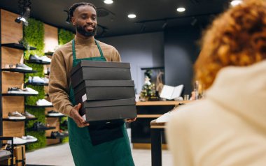 Ayakkabı mağazasında kutu taşıyan bir ayakkabı satıcısı. Ayakkabı mağazasında kutu taşıyan kaliteli bir ayakkabı satıcısı.