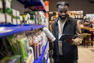 Elinde tablet tutan motosiklet malzemeleri satıcısı. Motosiklet malzemeleri satıcısı elinde tablet tutuyor.