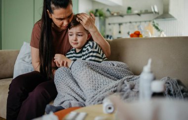 Anne öksüren ve üşüten küçük oğluna sarılıyor. Yüksek kaliteli fotoğraf. Annesi öksüren ve soğuk algınlığı geçiren oğluna sarılıyor.