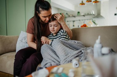 Anne öksüren ve üşüten küçük oğluna sarılıyor. Yüksek kaliteli fotoğraf. Annesi öksüren ve soğuk algınlığı geçiren oğluna sarılıyor.