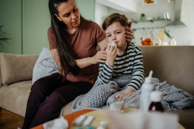 Yardım eden anne oğlunun burnunu silmesi için oğluna yardım ediyor. Yüksek kalite fotoğraf