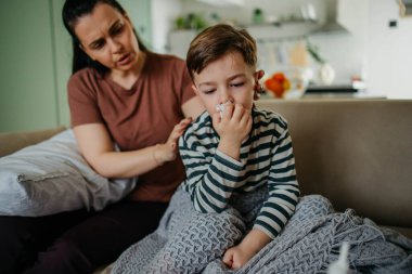 Yardım eden anne oğlunun burnunu silmesi için oğluna yardım ediyor. Yüksek kalite fotoğraf