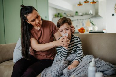 Yardım eden anne oğlunun burnunu silmesi için oğluna yardım ediyor. Yüksek kalite fotoğraf