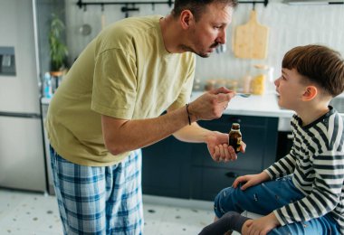 Baba oğluna ilaç veriyor baba da oğluna evde ilaç veriyor. Yüksek kalite fotoğraf