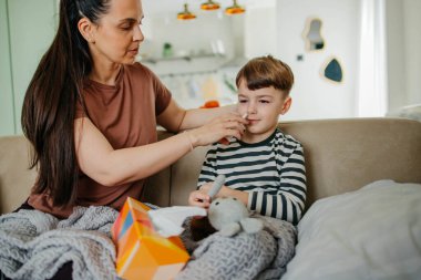 Annem oğlanlara burun spreyi sıkar. Yüksek kaliteli fotograf. Çocuklar burun spreyi sıkar.