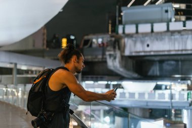 Yoğun bir şehir ortamında gece akıllı telefon tutan genç adam.