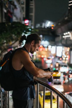Erkek fotoğrafçı, şehrin hareketli bir caddesinin fotoğraflarını çekiyor.