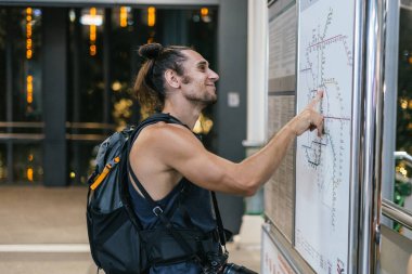 Ulaşım haritasına bakan bir turist istasyonda yolculuk planlıyor.