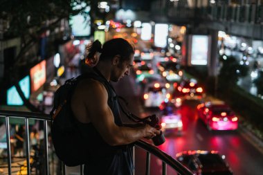 Elinde kamera olan bir adam, yoğun şehir trafiğini gece köprüden yakalıyor.