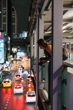 Yaya geçidindeki erkek gezgin aşağıdaki şehir hayatına bakıyor.