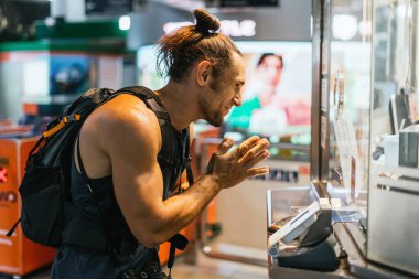 Sırt çantalı bir adam el ele tutuşmuş bir şekilde tezgahta duruyor.