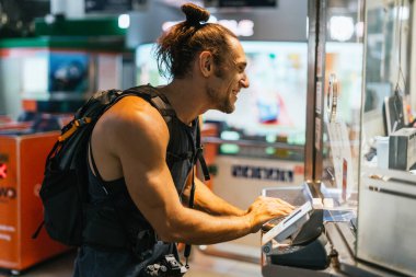 Bir servis gişesinde ödeme yaparken gülümseyen bir erkek yolcu.