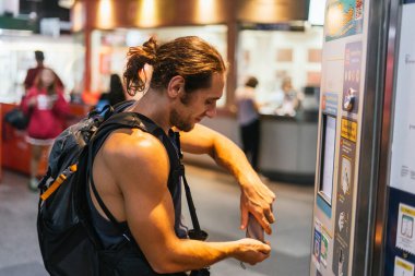 Otomatik bilet makinesinde toplu taşıma ücreti ödeyen bir yolcu.