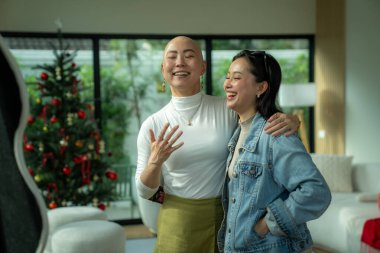 İki Asyalı kadın mutlu bir anı paylaşıyor ve Noel tatili boyunca kucaklaşıyorlar.