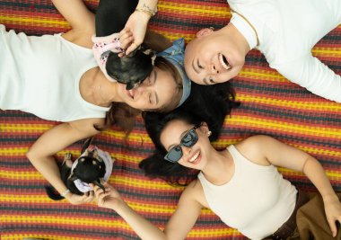 Küçük köpekleri ile bir paspasın üzerinde uzanmış mutlu genç kadınlar, bağlanıyor ve gülüyorlar.