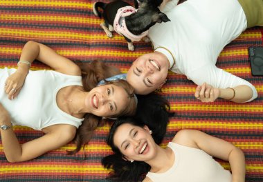 Üç gülümseyen kadın ve geleneksel bir paspasın üzerinde yatan bir köpek.