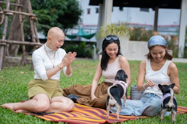 Parkta evcil hayvanlarıyla oynayan üç mutlu kadın.