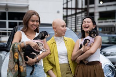 Küçük köpeklerini şehir ortamında tutarken gülen ve gülen arkadaşlar