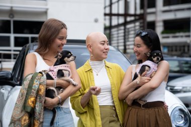 Üç arkadaş, biri kanserden kurtulan biri, dışarıda chihuahuaları ile dururken gülümsüyor.