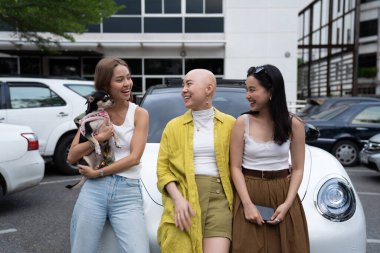 Çeşitli arkadaşlar küçük bir chihuahua köpeğiyle otoparkta gülüp eğleniyorlar.