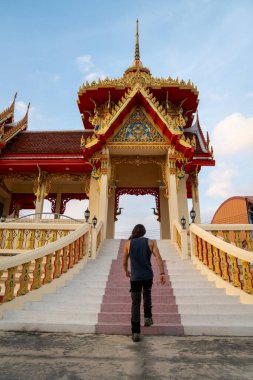 İnsanoğlu geleneksel bir tapınak kapısına doğru süslü adımlar atıyor, Tayland kültürünü keşfediyor.
