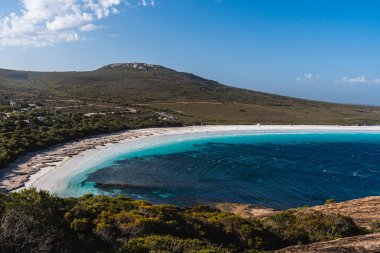 Lucky Körfezi 'nde pırıl pırıl turkuaz su, el değmemiş beyaz kum ve yeşil bir manzara var.