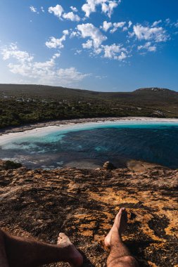 Çıplak bacaklar muhteşem bir okyanusun ve kayalık bir uçurumun sahil manzarasının tadını çıkarıyor.