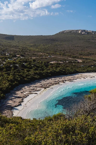 Kıyı bitkileri tarafından çerçevelenmiş beyaz kumlu sahili ve turkuaz suyu ile Hellfire Körfezi.