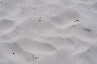 Sakin bir sahilde beyaz kum dalgalanmalar ve ince desenler yaratır.