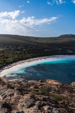 Beyaz kum, turkuaz su, kayalık sahil ve uzak tepelerle dolu Lucky Körfezi 'nin havadan görüntüsü.