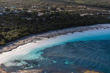 Kampçılar turkuvaz okyanus suları ve beyaz kumlarla uzak bir kumsalın keyfini çıkarıyorlar.