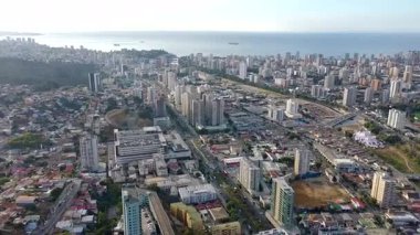 Yoğun bir kıyı şehrinin geniş bir insansız hava aracı görüntüsü. Yüksek binalar, yerleşim alanları ve kentsel altyapısı var. Kamera, okyanus ufkuna uzanan şehir manzarasını ortaya çıkaran pürüzsüz ve ince bir tava sergiliyor..