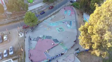 Şehir merkezindeki bir kaykay parkının statik drone görüntüsü kaykaycıları şehir ortamında rampa ve bowling oynarken gösteriyor..